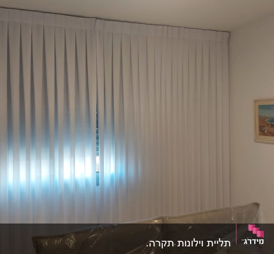 וילון אנכי לבן מותקן על חלון